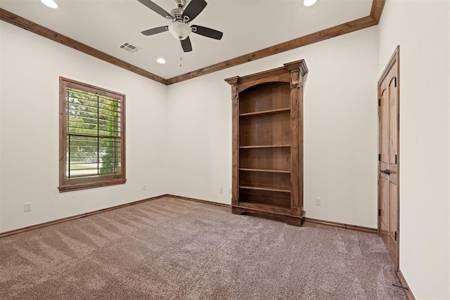 empty room featuring ceiling fan, crown molding, and carpet flooring