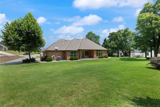 rear view of house featuring cooling unit and a lawn