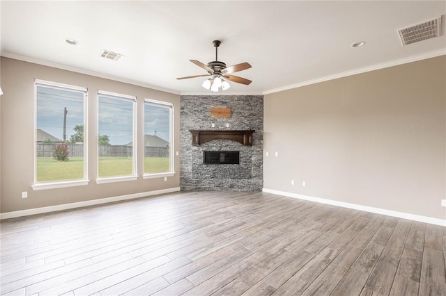 unfurnished living room featuring crown molding, ceiling fan, light hardwood / wood-style flooring, and a stone fireplace