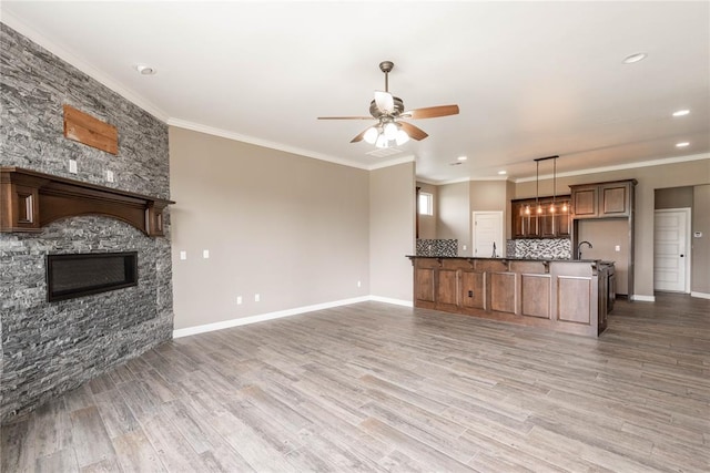 kitchen with decorative light fixtures, a fireplace, hardwood / wood-style floors, ceiling fan, and crown molding