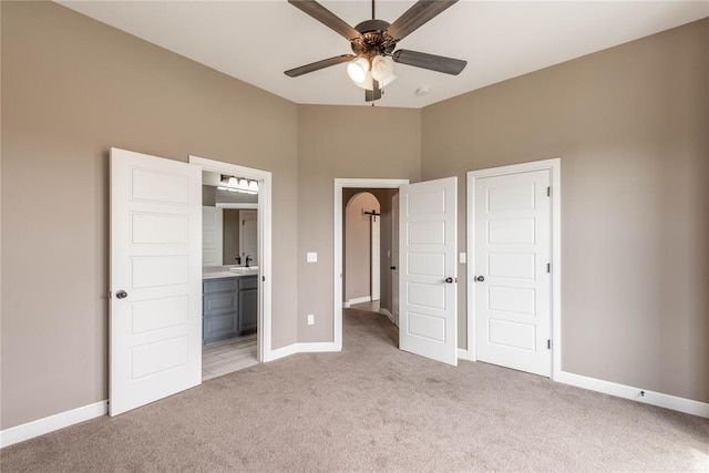 unfurnished bedroom featuring ceiling fan, light carpet, and connected bathroom