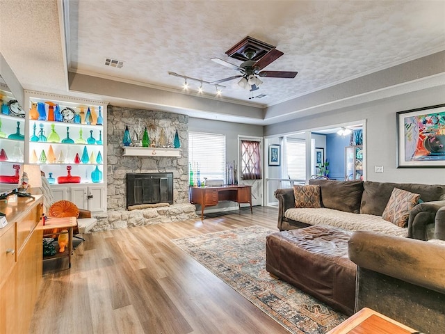 living room featuring a fireplace, ceiling fan, a textured ceiling, and ornamental molding