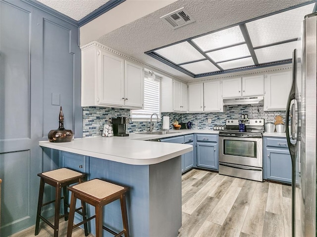 kitchen featuring kitchen peninsula, a breakfast bar, white cabinets, appliances with stainless steel finishes, and sink