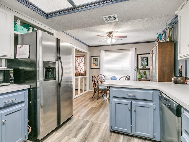 kitchen featuring appliances with stainless steel finishes, white cabinetry, ornamental molding, and light wood-type flooring