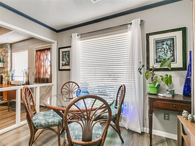 dining area with a textured ceiling, light wood-type flooring, and crown molding