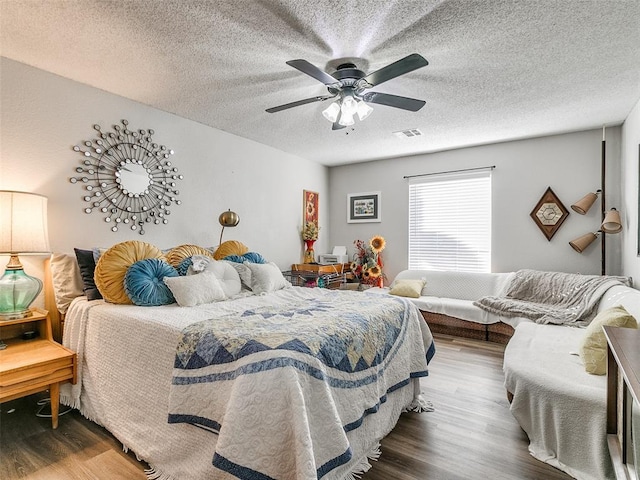 bedroom with hardwood / wood-style flooring, a textured ceiling, and ceiling fan