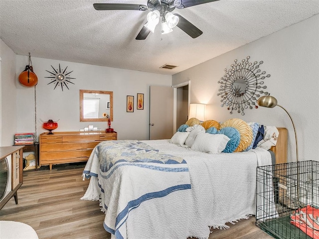 bedroom featuring hardwood / wood-style flooring, a textured ceiling, and ceiling fan