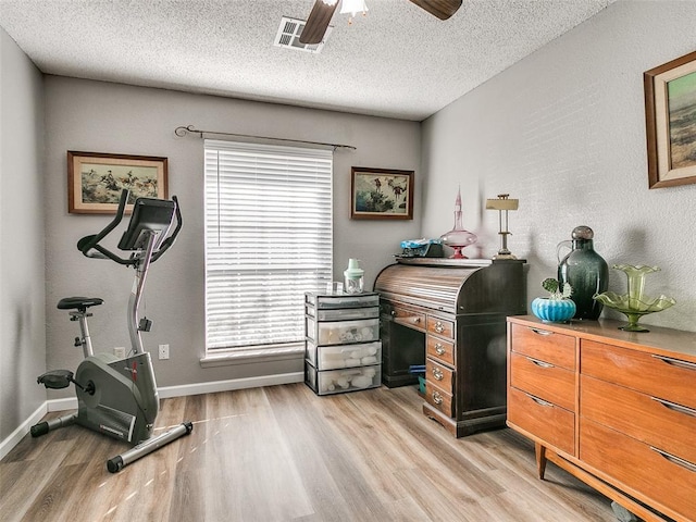 home office with a textured ceiling, light wood-type flooring, and ceiling fan