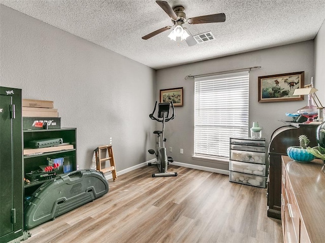 workout area featuring a textured ceiling, ceiling fan, and hardwood / wood-style flooring