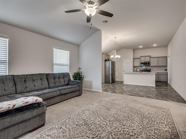 carpeted living room featuring ceiling fan with notable chandelier and vaulted ceiling