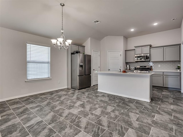 kitchen featuring stainless steel appliances, vaulted ceiling, gray cabinets, and a center island with sink