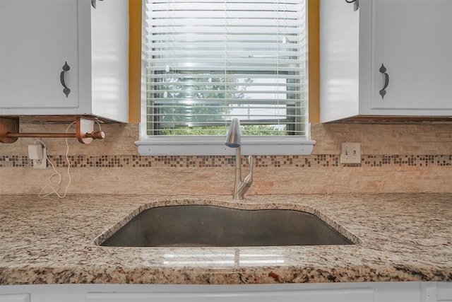 kitchen featuring light stone countertops, sink, white cabinets, and tasteful backsplash