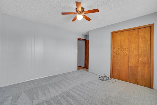 unfurnished bedroom featuring a textured ceiling, ceiling fan, carpet flooring, and a closet