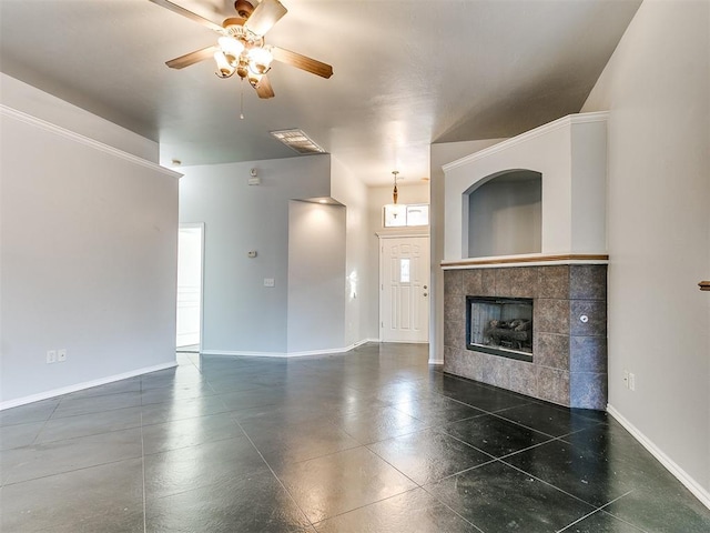 unfurnished living room with a tiled fireplace and ceiling fan