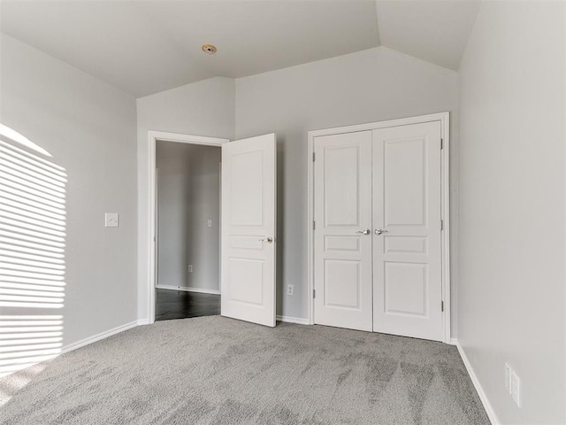 unfurnished bedroom featuring a closet, carpet, and vaulted ceiling