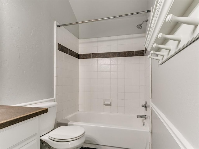 full bathroom featuring tiled shower / bath, vanity, and toilet