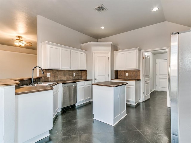 kitchen featuring stainless steel appliances, white cabinets, lofted ceiling, and tasteful backsplash