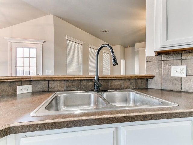 room details with sink, decorative backsplash, and white cabinetry