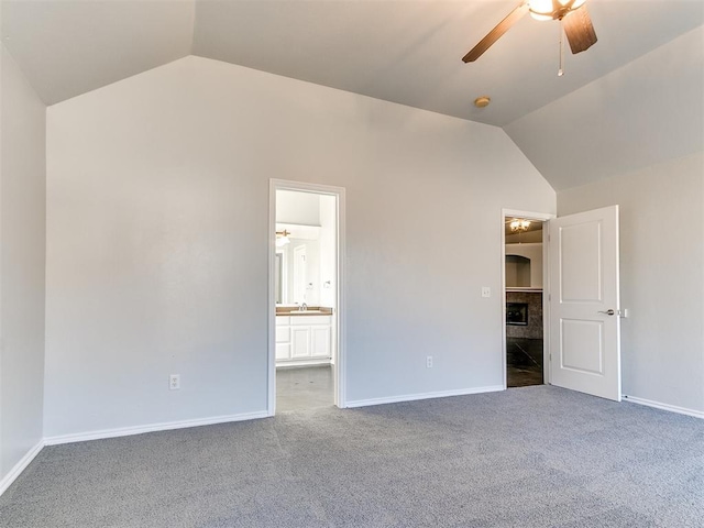 unfurnished bedroom with lofted ceiling, ensuite bath, dark colored carpet, and ceiling fan