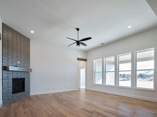 unfurnished living room featuring a brick fireplace, ceiling fan, and light hardwood / wood-style floors