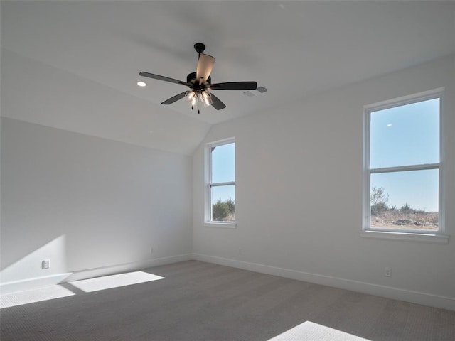 carpeted spare room featuring ceiling fan, a healthy amount of sunlight, and lofted ceiling