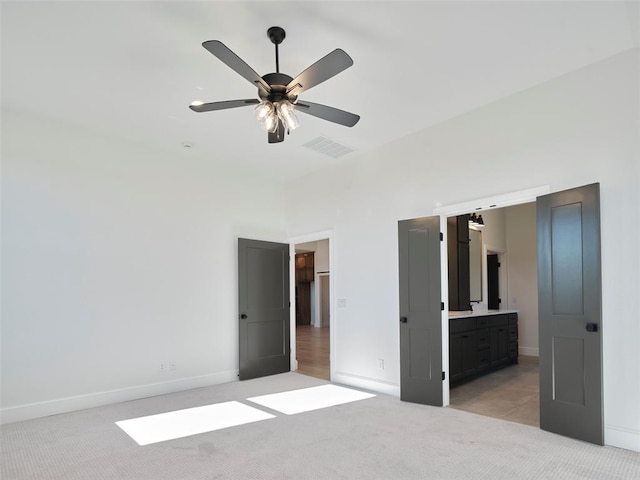 unfurnished bedroom featuring connected bathroom, ceiling fan, and light colored carpet