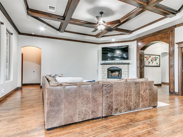 living room with ornamental molding, light hardwood / wood-style floors, and a stone fireplace