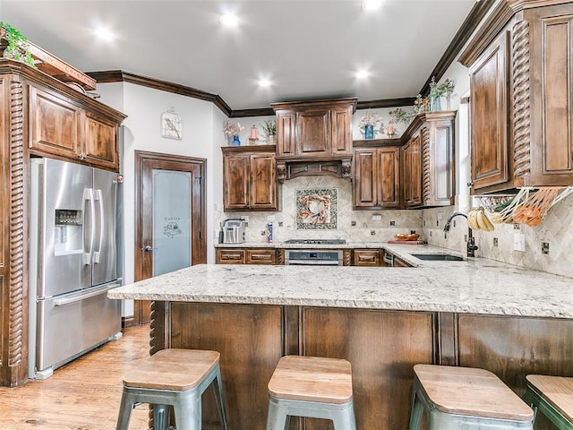 kitchen with stainless steel appliances, sink, a kitchen breakfast bar, kitchen peninsula, and decorative backsplash