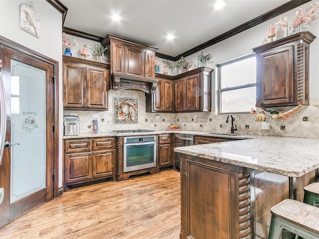 kitchen featuring stainless steel appliances, light hardwood / wood-style floors, crown molding, backsplash, and sink