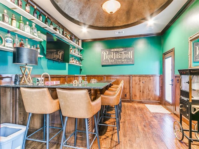 bar featuring ornamental molding and hardwood / wood-style floors