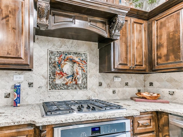 kitchen with light stone countertops, custom exhaust hood, tasteful backsplash, and appliances with stainless steel finishes