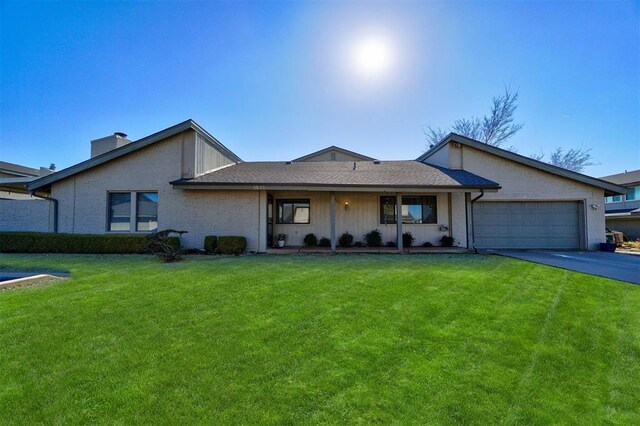 ranch-style house featuring an attached garage, a chimney, a front yard, and aphalt driveway