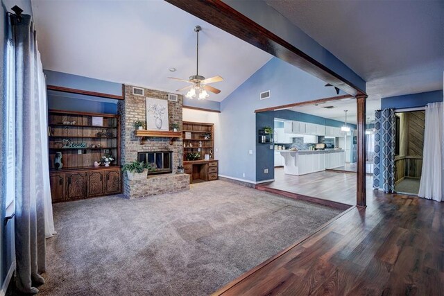 living area with ceiling fan, visible vents, a brick fireplace, wood finished floors, and baseboards