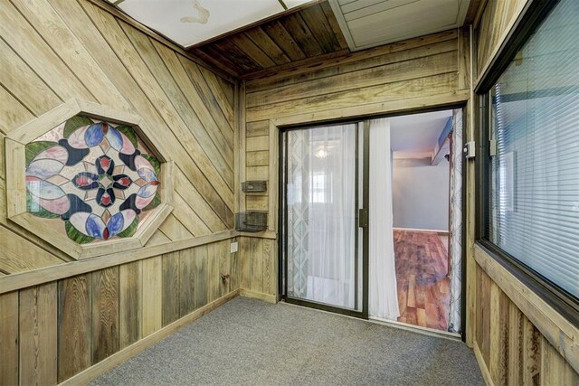interior space featuring wooden walls and carpet