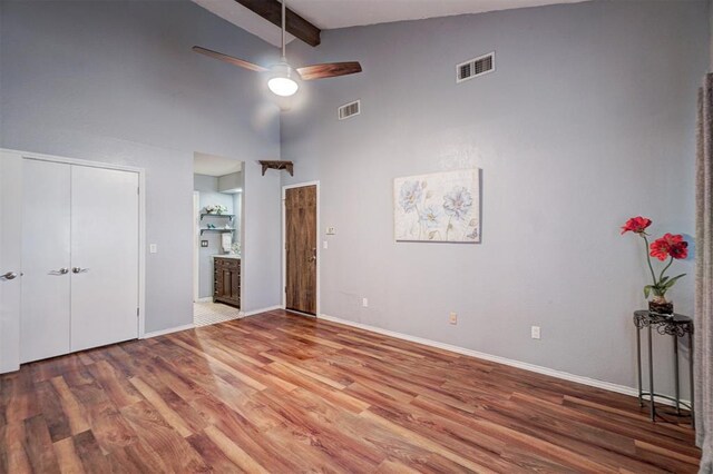 unfurnished bedroom with visible vents, beam ceiling, and wood finished floors