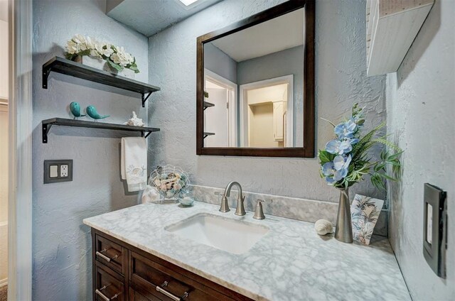 bathroom with vanity and a textured wall