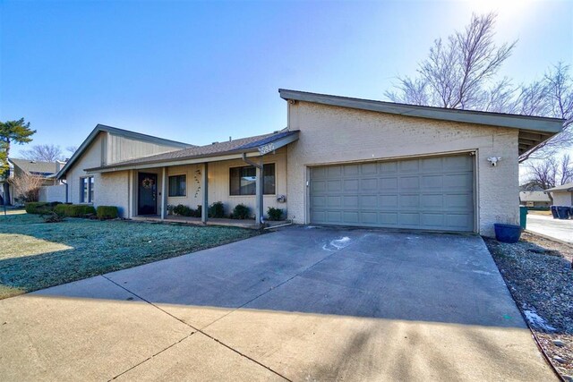 view of front of home with a porch, a garage, driveway, and a front yard