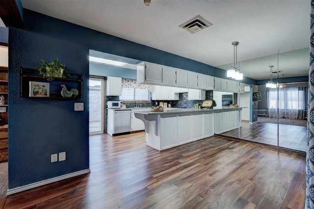 kitchen featuring white cabinets, dark wood finished floors, a wealth of natural light, stainless steel dishwasher, and visible vents