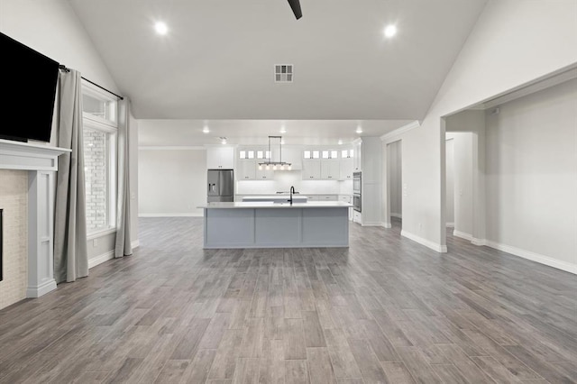 unfurnished living room with visible vents, a fireplace, a sink, and vaulted ceiling