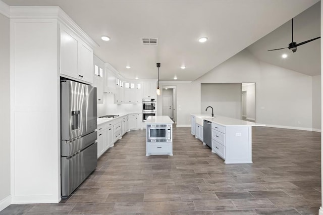 kitchen with visible vents, an island with sink, ceiling fan, a sink, and appliances with stainless steel finishes