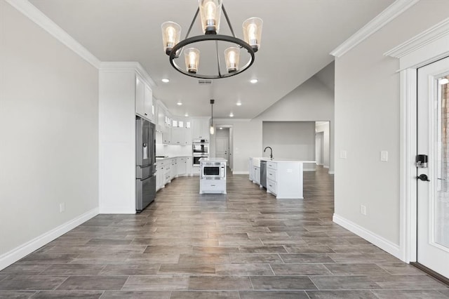 kitchen with a chandelier, light countertops, appliances with stainless steel finishes, white cabinetry, and a sink