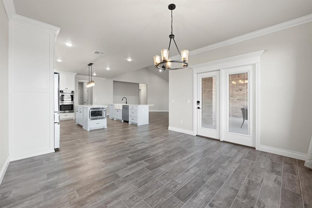 unfurnished living room with crown molding, wood finished floors, visible vents, and baseboards