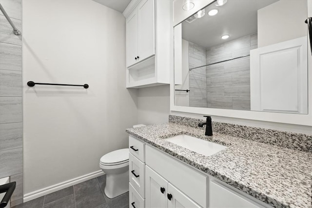 bathroom featuring a tile shower, toilet, vanity, and baseboards