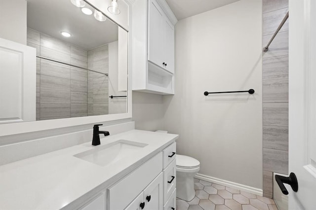 bathroom with tile patterned flooring, baseboards, toilet, a tile shower, and vanity