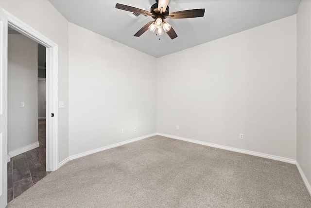 carpeted spare room featuring baseboards and a ceiling fan