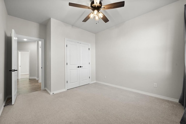 unfurnished bedroom featuring ceiling fan, baseboards, a closet, and light carpet