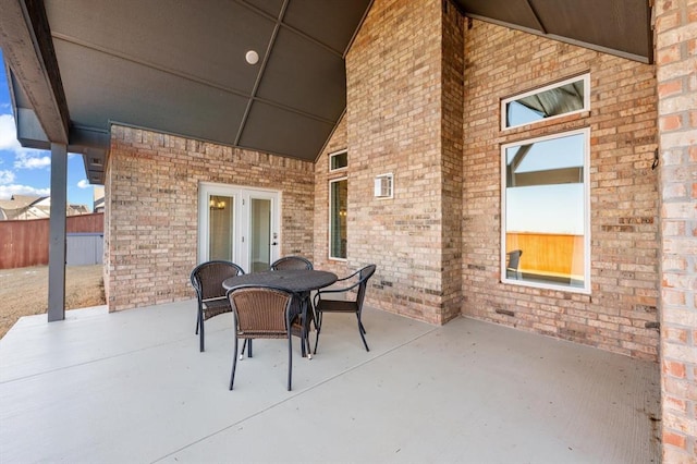 view of patio with french doors, outdoor dining area, and fence