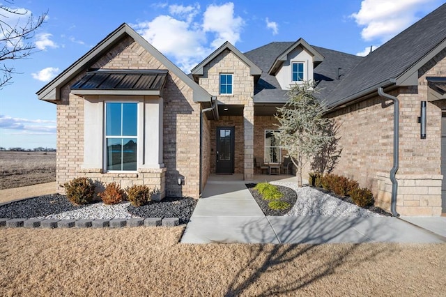 view of front of home with brick siding, roof with shingles, metal roof, stone siding, and a standing seam roof