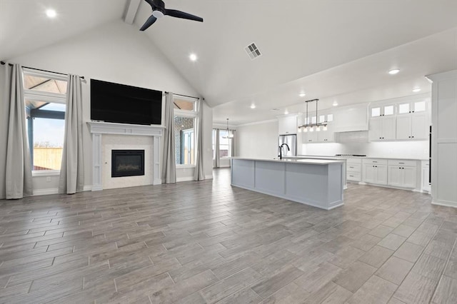 kitchen with a glass covered fireplace, a healthy amount of sunlight, open floor plan, and a ceiling fan