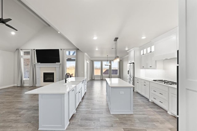 kitchen with a spacious island, gas stovetop, stainless steel fridge, a glass covered fireplace, and open floor plan